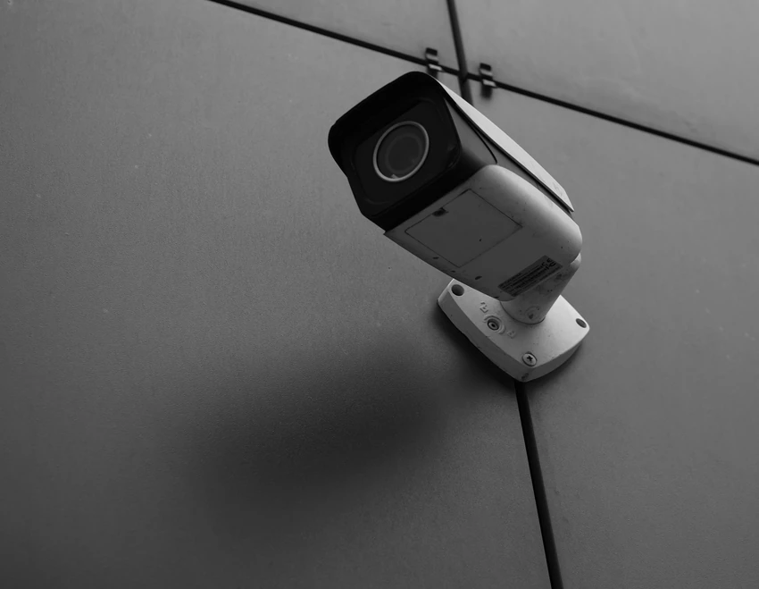 Cámara de videovigilancia sobre fachada de vidrio estructural, en blanco y negro